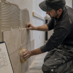 Pose carrelage mural : carreleur sur tasseau horizontal pour aligner les carreaux